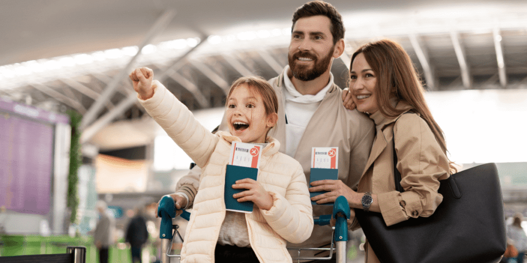 A family with a child in a shopping cart navigates through an airport terminal.
