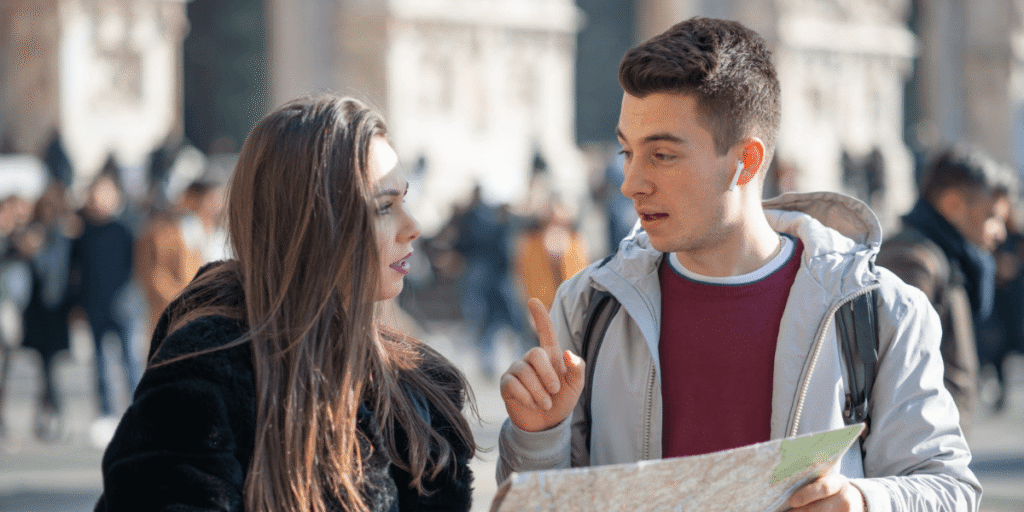 Two travelers in a city, studying a map together while engaging in a conversation