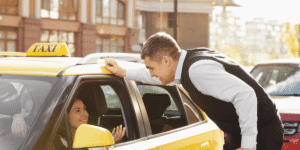 A man assists a woman as she enters a taxi, demonstrating kindness and support in a busy urban setting.