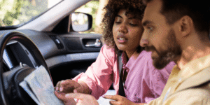 A man and woman seated in the front seats of a car, both looking forward with smiles.