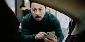 A driver in a car, attentively steering while a phone rests on the dashboard, highlighting potential distractions.