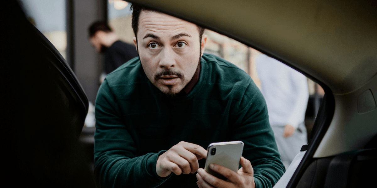 A driver in a car, attentively steering while a phone rests on the dashboard, highlighting potential distractions.